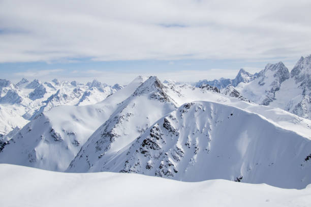 istock Snowy Mountains peaks in the clouds blue sky Caucasus 1358768330