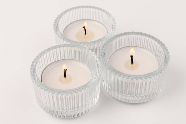 istock Burning tea candles in a glass holder, isolated on white. Space for text 1358771219