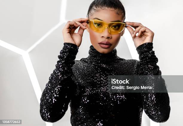 Elegant African American Woman With Her Hair Pulled Back And Wearing A Shiny Black Dress Stock Photo - Download Image Now