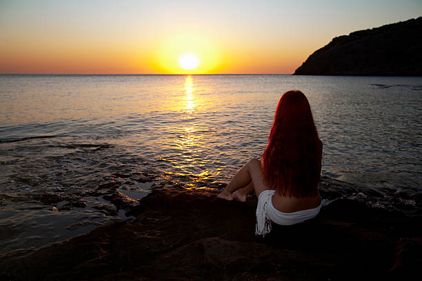 Naked woman watching sunrise stock photo