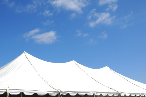 Top of a large event tent for entertainment against a blue sky