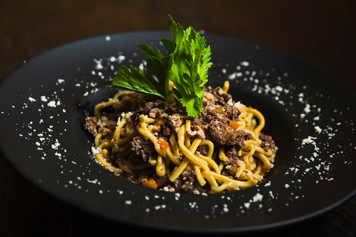 Spaghetti with venison sauce on background black table