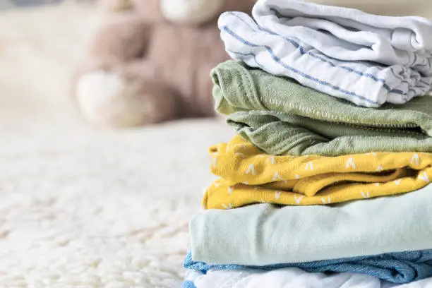 Colored baby clothing to lie in a stack on the bed