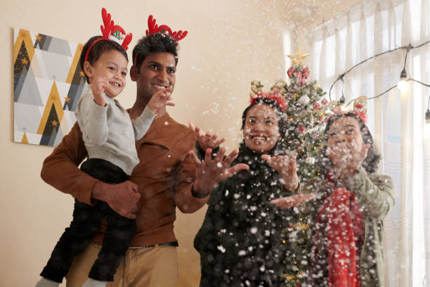Happy Family Throwing Artificial Snow Happy family throwing artificial snow at home when celebrating Christmas artificial snow stock pictures, royalty-free photos & images