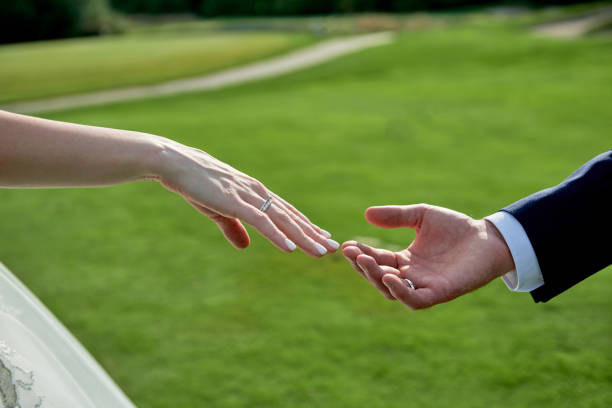 istock Newlywed couple's hands with wedding rings on golf course background, copy space. Wedding couple, bride and groom, hands with rings, closeup 1358780246