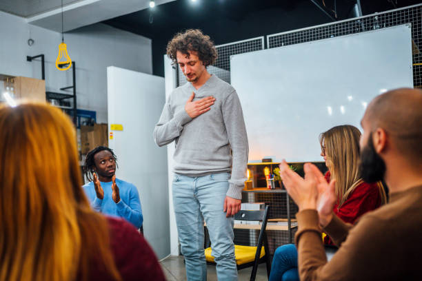 Man introducing himself at AA meeting Young man standing up to share his experience on an alcoholic anonymous meeting drug addiction tattoos stock pictures, royalty-free photos & images
