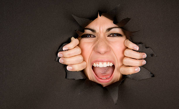 spremere in volto di donna frustrata rottura attraverso barriera - human mouth paper screaming hole foto e immagini stock