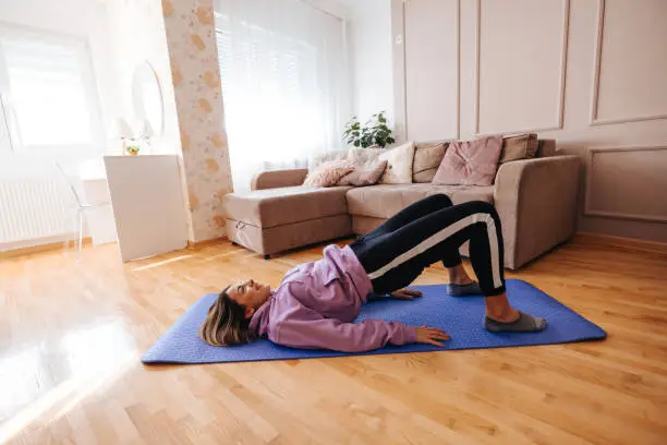 Photo of Fit young woman doing glute bridge exercise at home