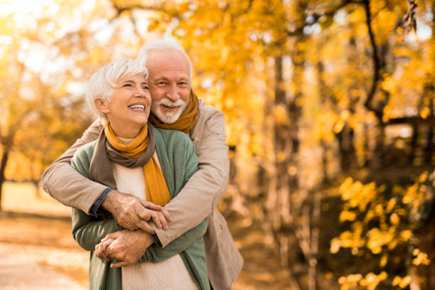 feliz pareja de mayores disfrutando de un día de otoño juntos. - autumn women park forest fotografías e imágenes de stock