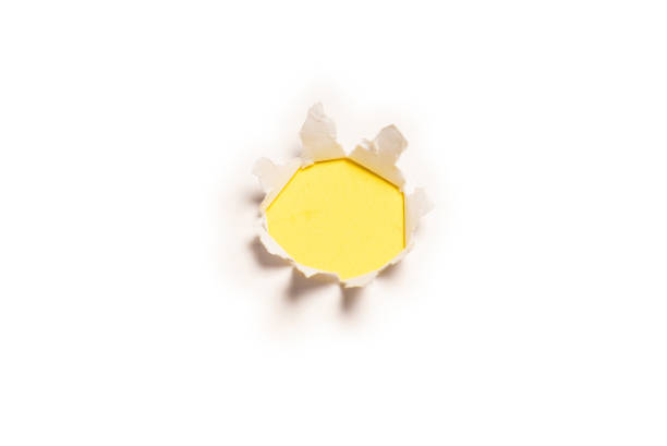istock A hole in a white paper on a yellow background. 1358792962