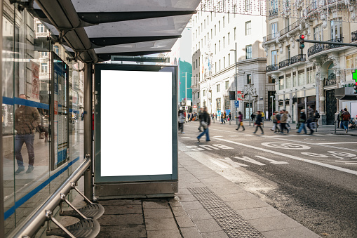 A bus stop in a city with a blank billboard for advertisements