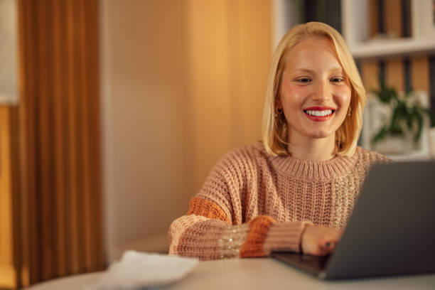 istock Smiling young woman, checking her new laptop, at home, while typing. 1358796945