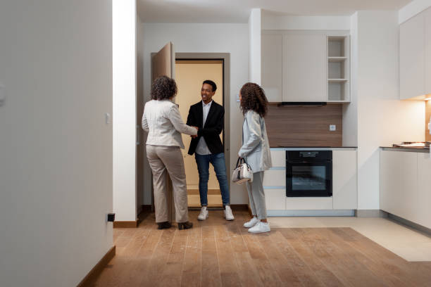 istock Real Estate Agent Welcoming Clients On Front Door 1358799782