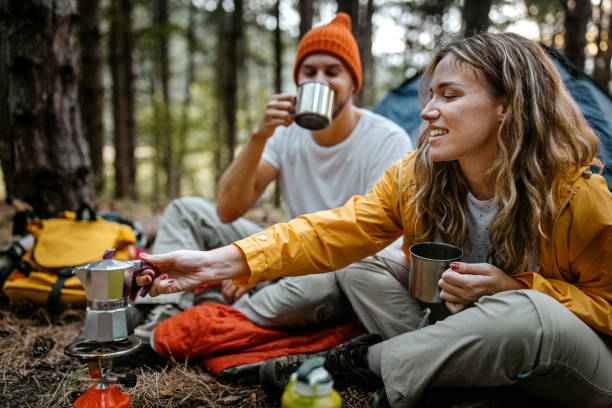 giovane coppia che prepara il caffè durante le escursioni - camping foto e immagini stock