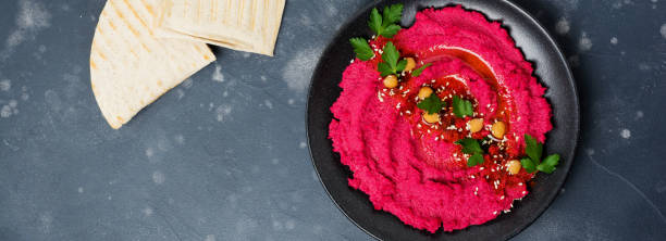 istock Homemade beetroot hummus in black ceramic dish on old dark concrete background. Selective focus. Top view. 1358800571