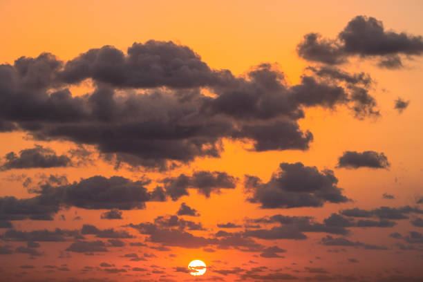 brilliant sun setting over ocean with ckouds