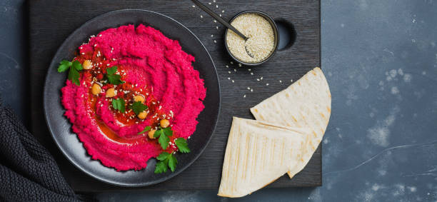istock Homemade beetroot hummus in black ceramic dish on old dark concrete background. Selective focus. Top view. 1358800809