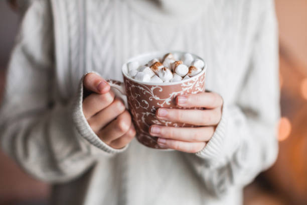 istock Girl in a cozy knitted sweater drinking coffee from a mug 1358804513