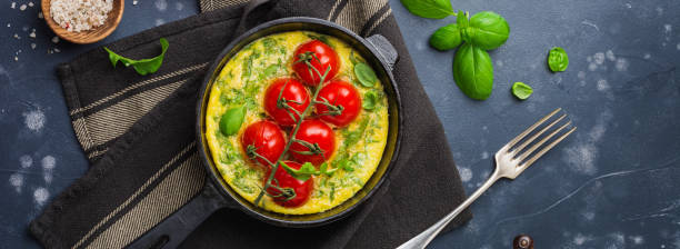 istock Frittata with arugula, potatoes and cherry tomatoes in iron pan on old stone table background. Top view. 1358806494