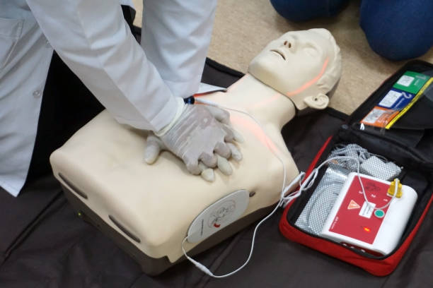 thoraxkompressionen durch einen schüler auf einem simulationsdummy während der grundlegenden lebenserhaltung mit einem automatischen externen defibrillator. simulationstrainingsszenario - chest compressions stock-fotos und bilder