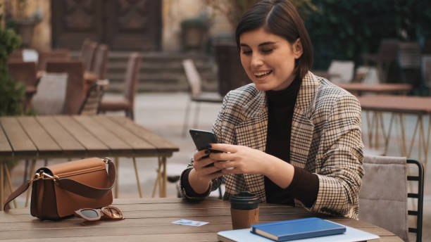 istock Attractive cheerful entrepreneur looking happy texting on smartp 1358810666