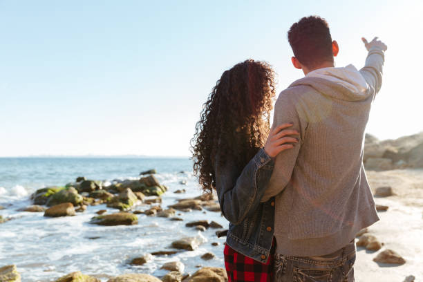 istock African loving couple walking outdoors at beach. 1358811264