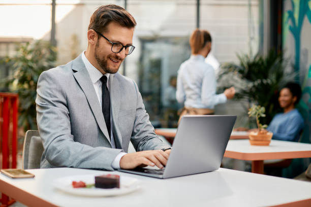 istock Happy businessman working on laptop in a cafe. 1358813738