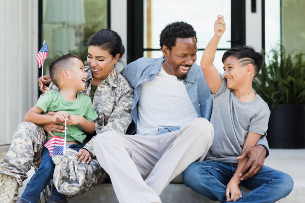 istock Sitting on front stoop military family waves small American flags 1358818014