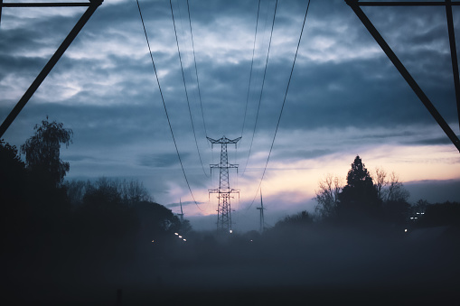 A beautiful view of foggy or misty day and power line tower over farmlands during the early morning