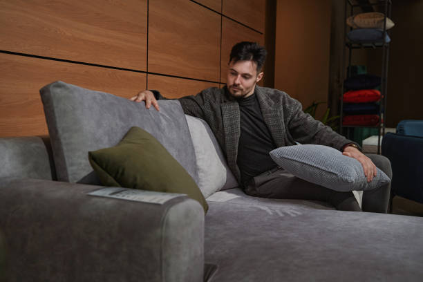 istock Concentrated guy choosing new pillows for couch 1358824610