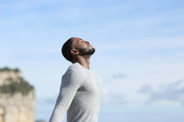 homme à la peau noire relaxant respirant de l’air frais à l’extérieur - exercice de respiration photos et images de collection