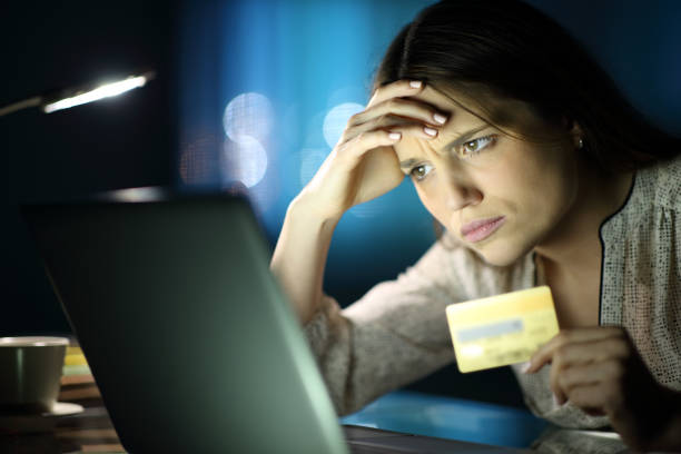 Worried woman in the night buying online at home stock photo