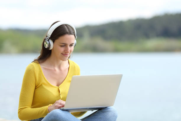 istock Woman wearing headset using laptop in a lake 1358826861