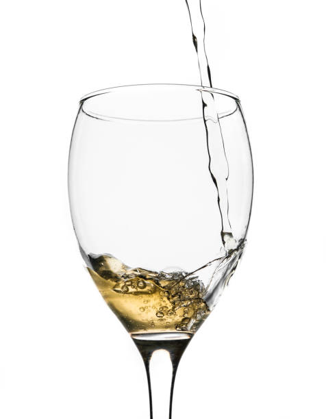 istock White wine pouring in a glass, white background. 1358828062