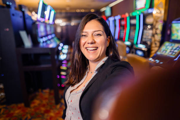 スロットマシン近くの幸せな女性カジノプレーヤーの肖像画 - casino worker ストックフォトと画像