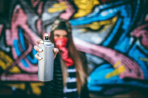 Artista de graffiti apuntando una lata de spray a la cámara photo