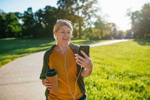 istock Senior woman outdoors on spring day in park using phone for video call 1358830501