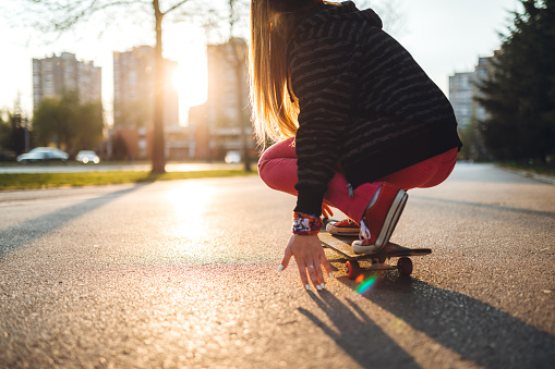 A close-up of a young woman kneeling on a skateboard.