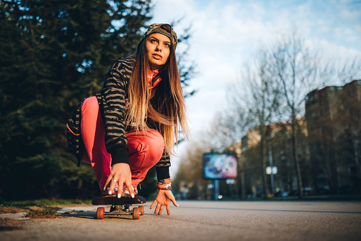 A young urban brunette woman skateboarding on the street.
