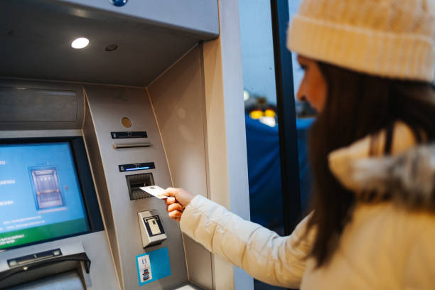 istock Women using ATM machine to withdraw money 1358832332