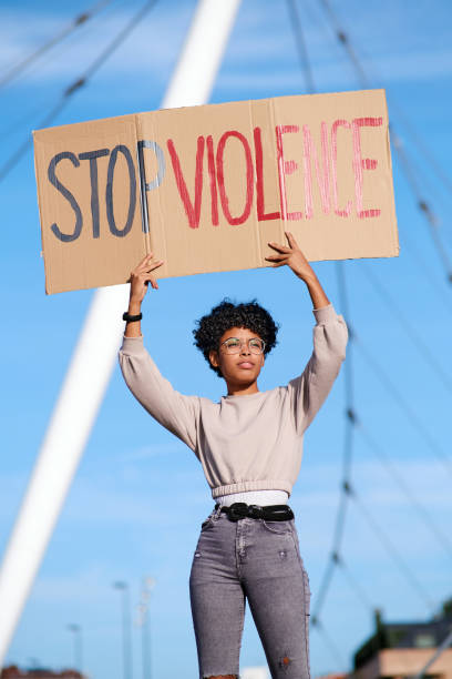istock An African American young protester raising arms and holding a placard protesting against violence against women. 1358833530