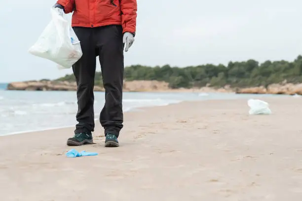 Photo of Volunteer woman cleaning plastic and microplastics from the sand at the beach