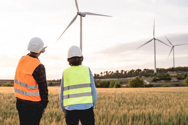 istock Sustainable energy industry - Engineers working at alternative renewable wind energy farm - Soft focus on left man hat 1358834010