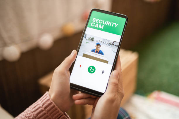 istock Delivery man ringing door bell on cctv secure camera system on mobile phone app 1358834180