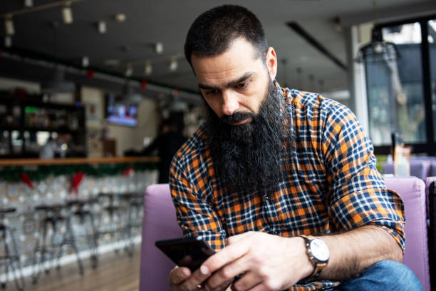 istock Caucasian male freelancer using cell phone at coffee shop 1358839147