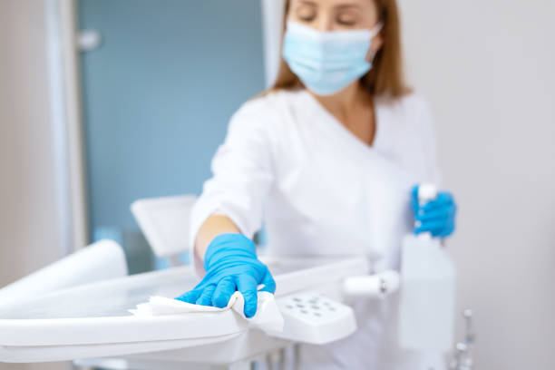 Nurse in protective gloves sanitizing dental chair Nurse in protective gloves cleaning work surface at stomatology clinic, sanitizing table with disinfectant spray bottle, washing dental chair with towel, selective focus surface disinfection stock pictures, royalty-free photos & images
