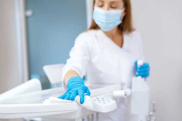 Nurse in protective gloves sanitizing dental chair Nurse in protective gloves cleaning work surface at stomatology clinic, sanitizing table with disinfectant spray bottle, washing dental chair with towel, selective focus cleaning cupboard stock pictures, royalty-free photos & images