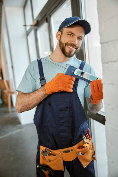 istock Cheerful man fixing window with silicone adhesive gun 1358842543