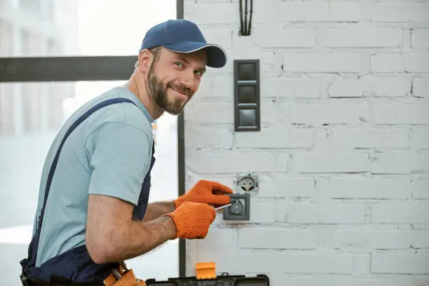 Photo of Cheerful young man fixing electrical wall socket