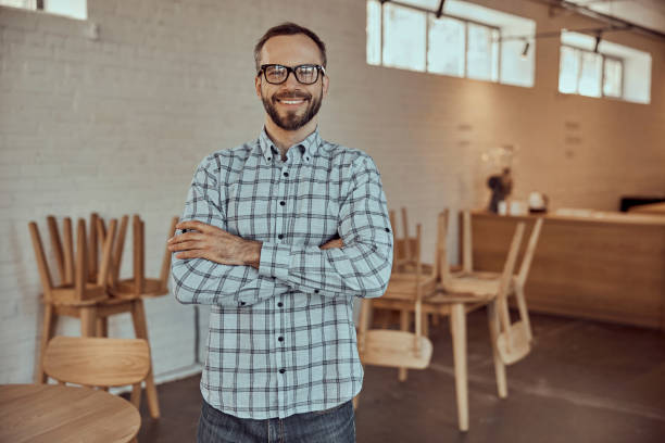 istock Cheerful bearded man in glasses standing in cafe 1358842805
